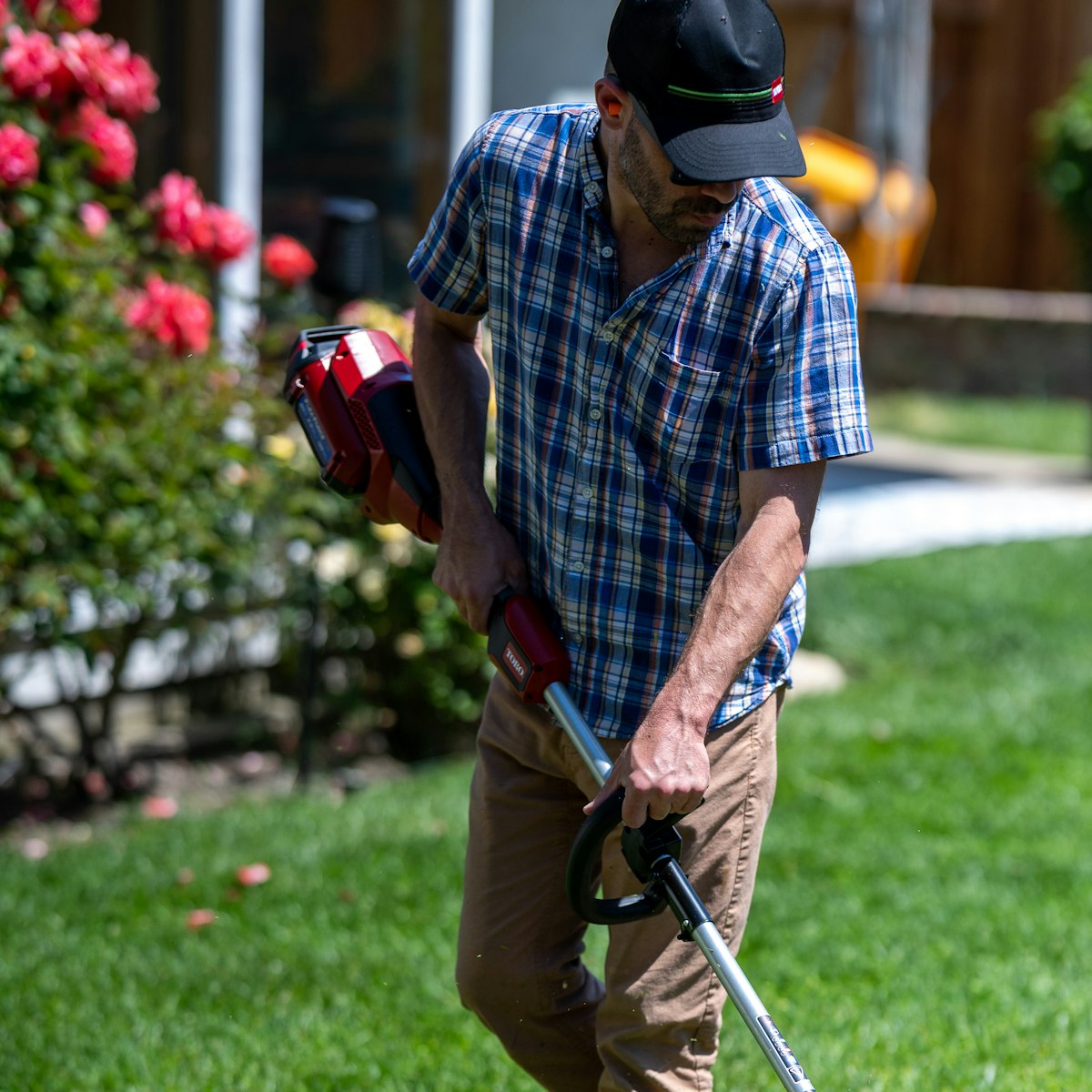 Lawn care professional using powered trimming equipment to maintain clean grass edges around a residential landscape, representing Lawn Care services near me.