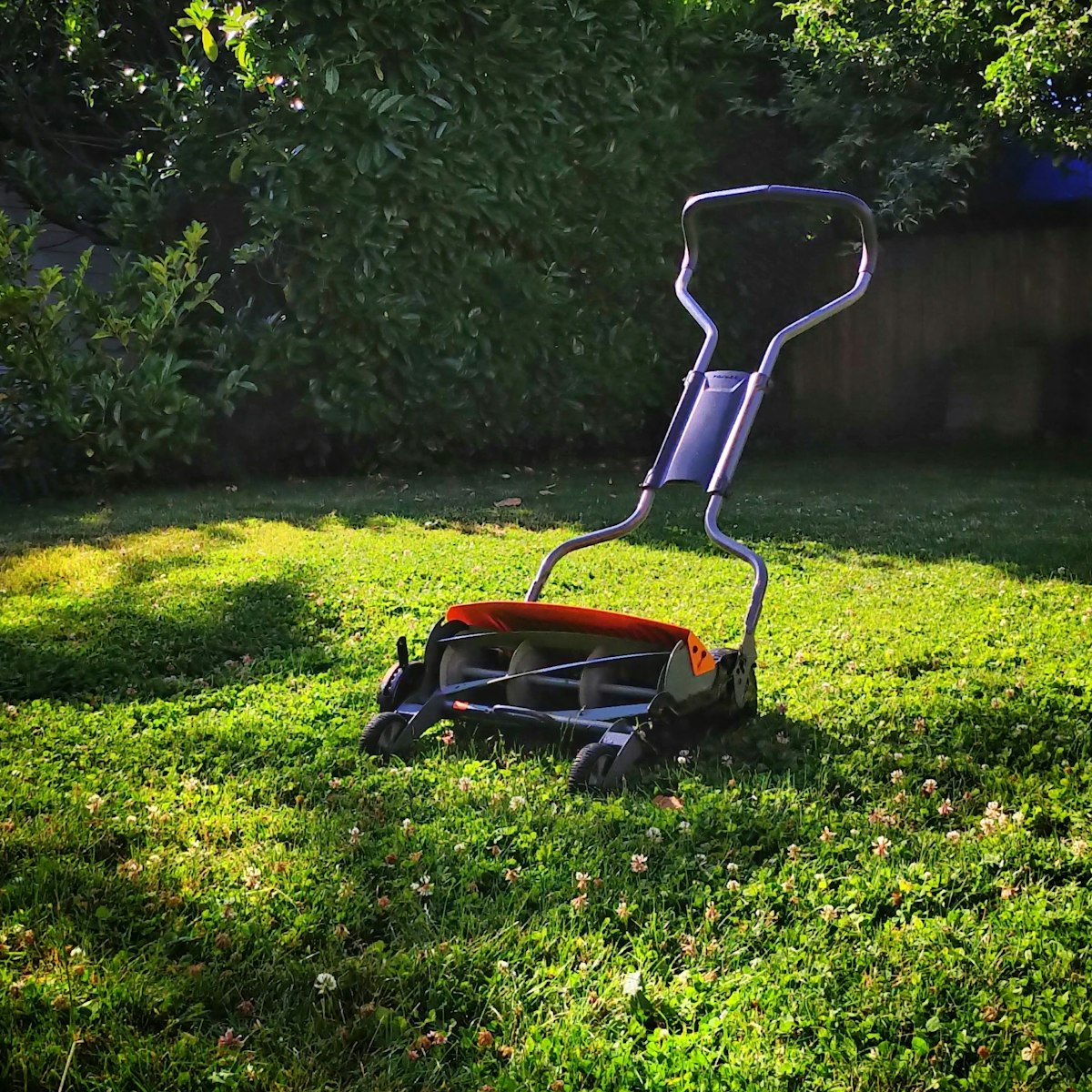 Manual lawn mower positioned on a maintained residential lawn, representing Dependable Lawn Care in Dover, NH.
