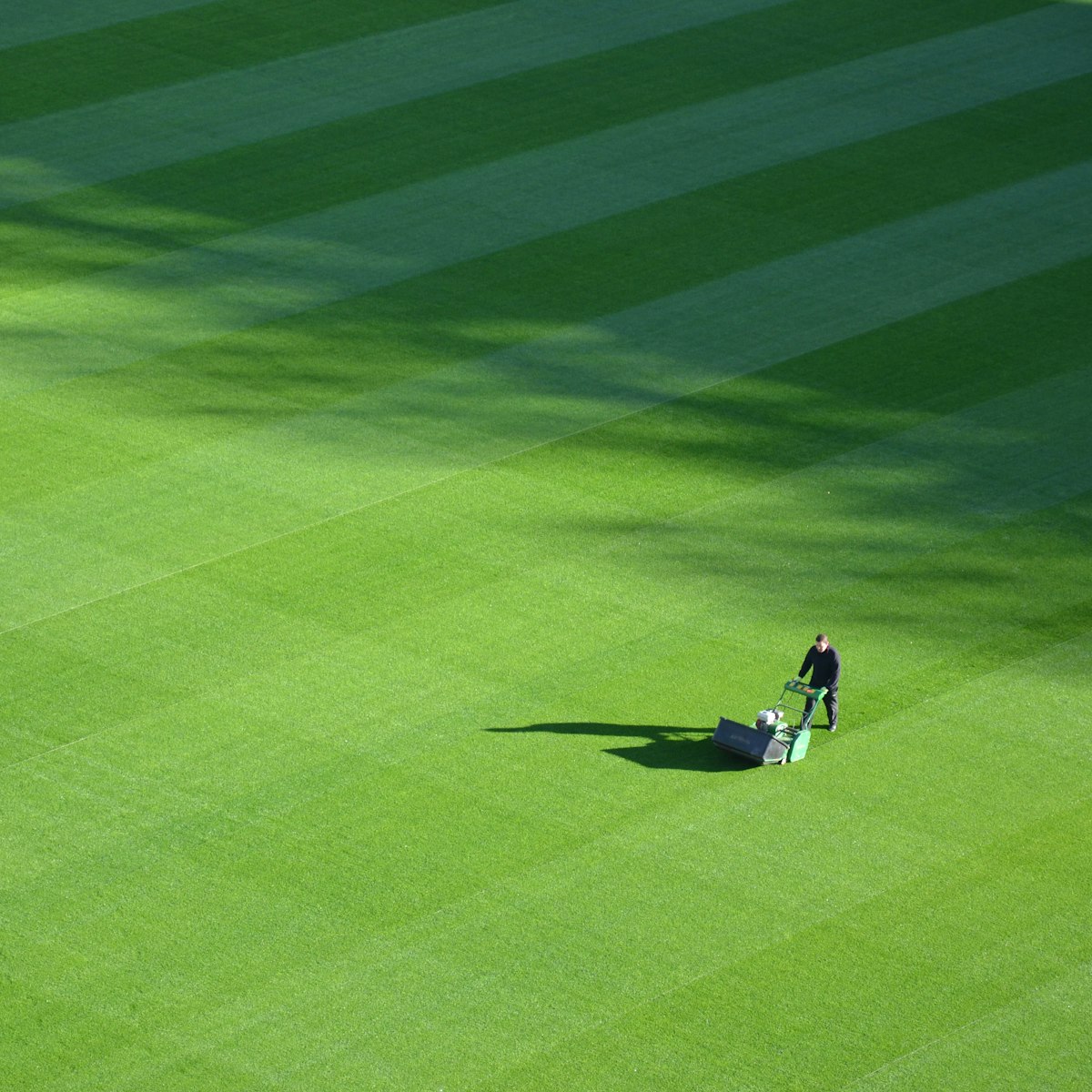 Landscaping professional mowing a large, neatly striped green lawn, representing Lawn Care in Barrington, NH.