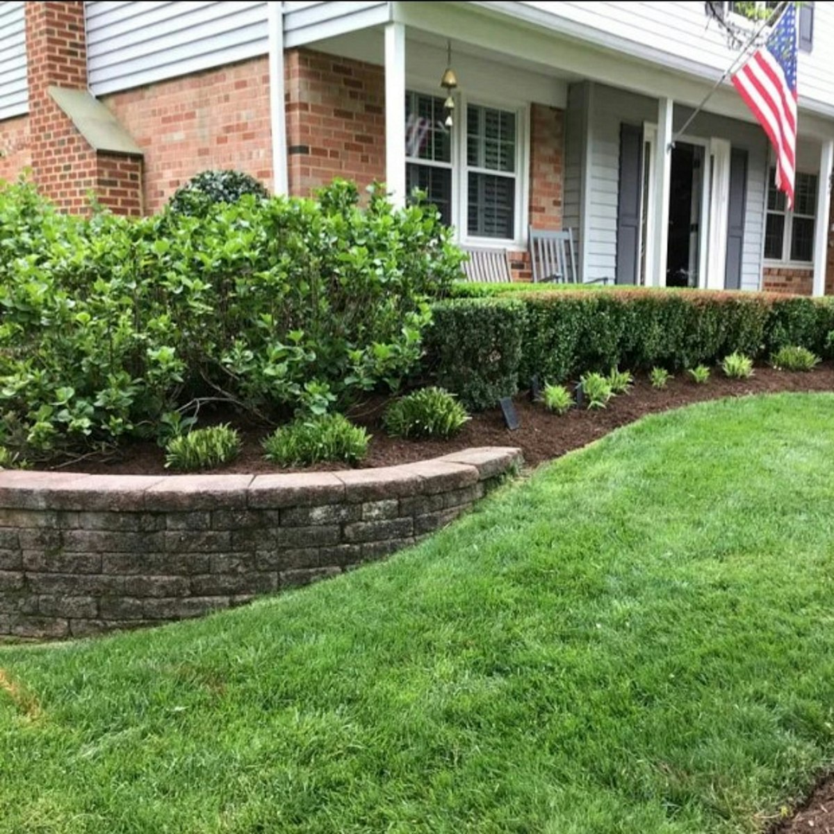 Well-maintained residential lawn with neatly trimmed hedges, mulched garden beds, and defined landscape edging, representing Lawn Care services near me.