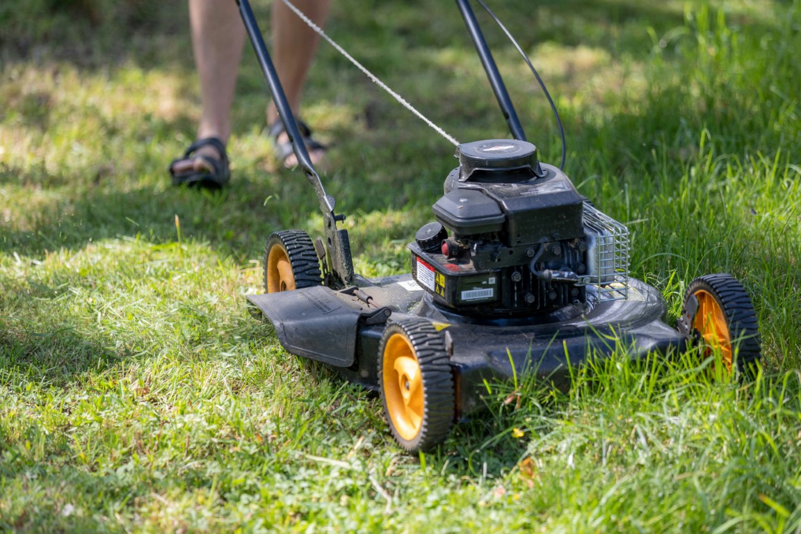 Push lawn mower cutting grass during lawn care services near me