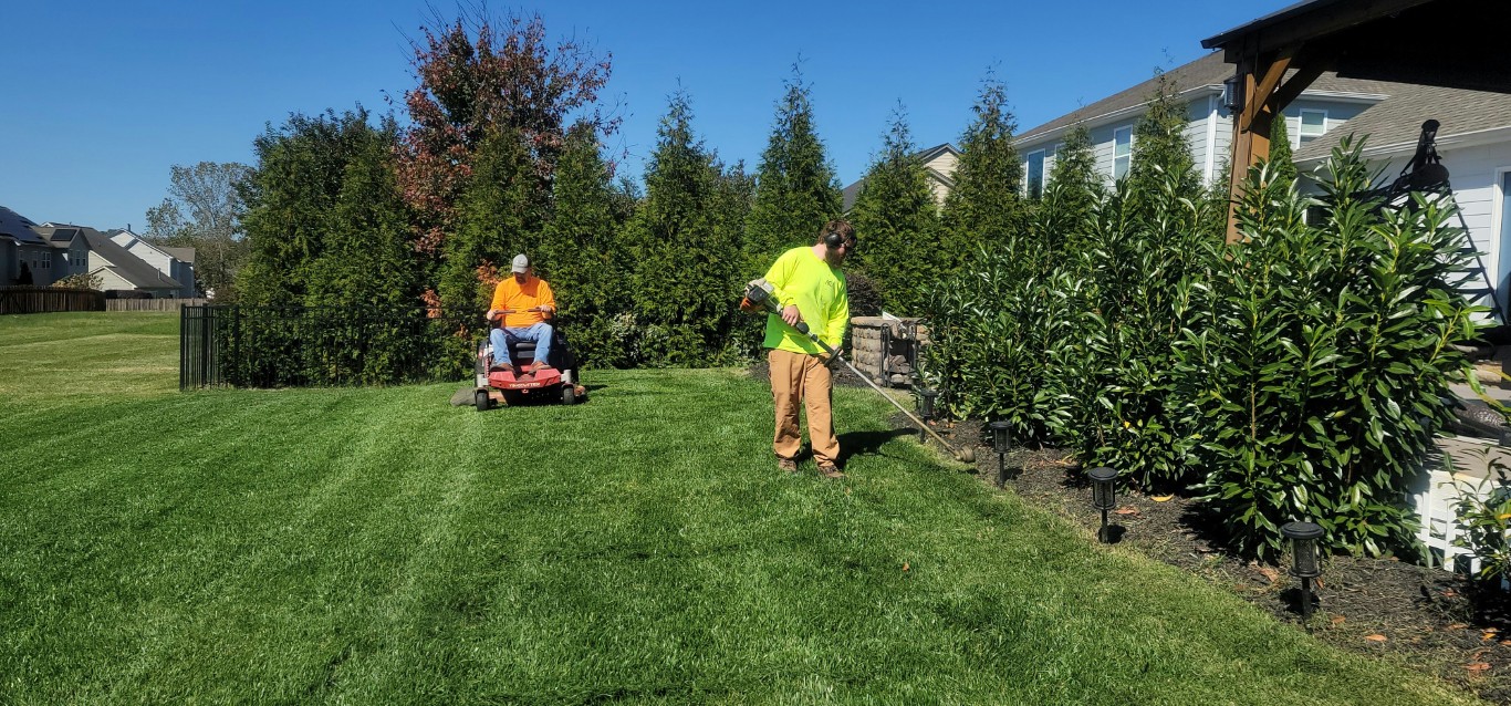 Landscaping crew mowing and trimming a residential lawn during lawn care services near me