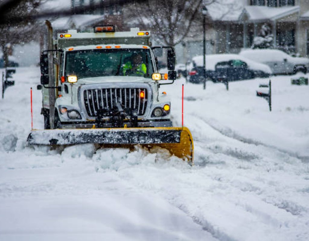 Professional snow plowing team working in Dover, NH driveway